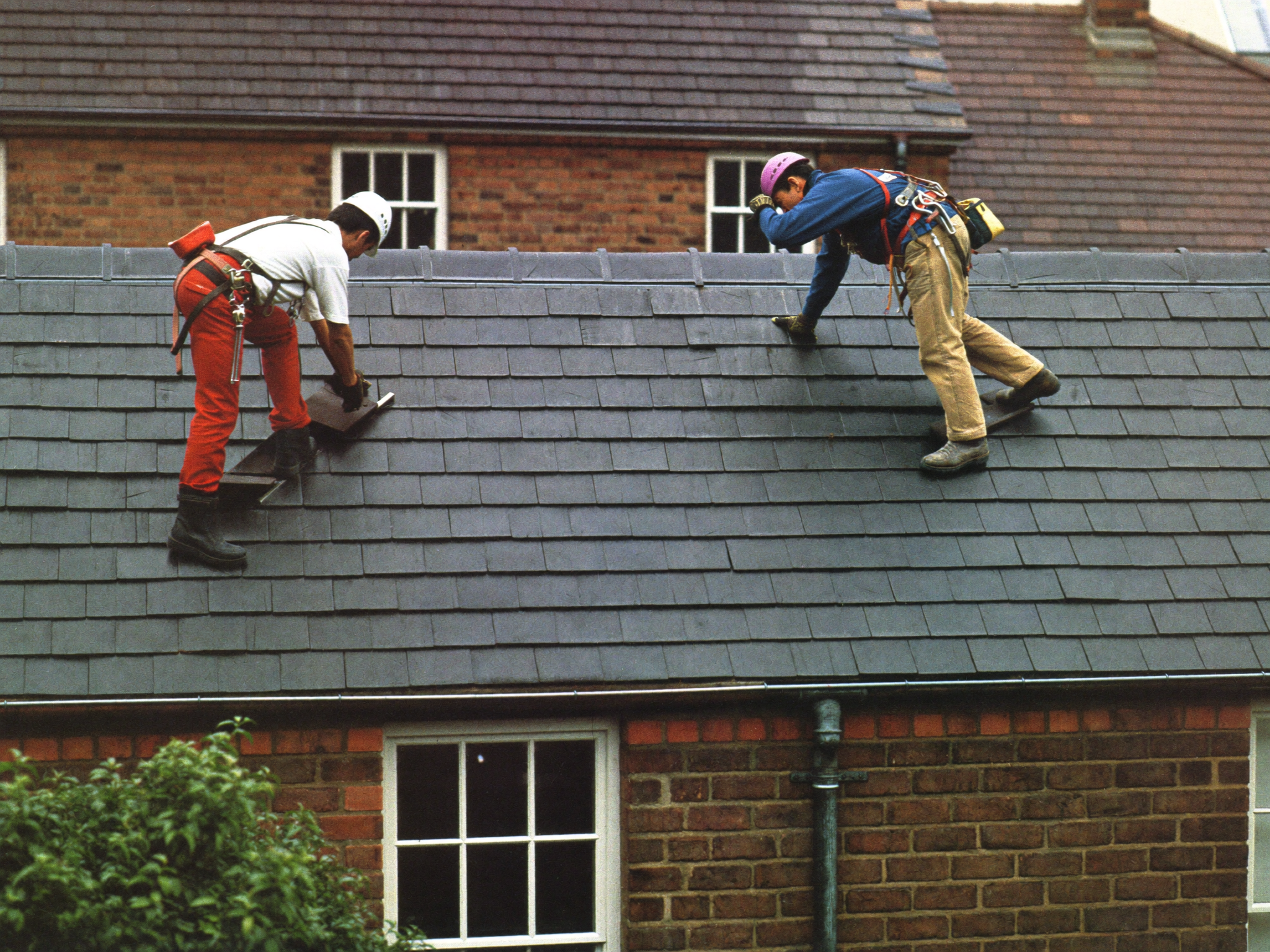Two roofing contractors working on a slate roof